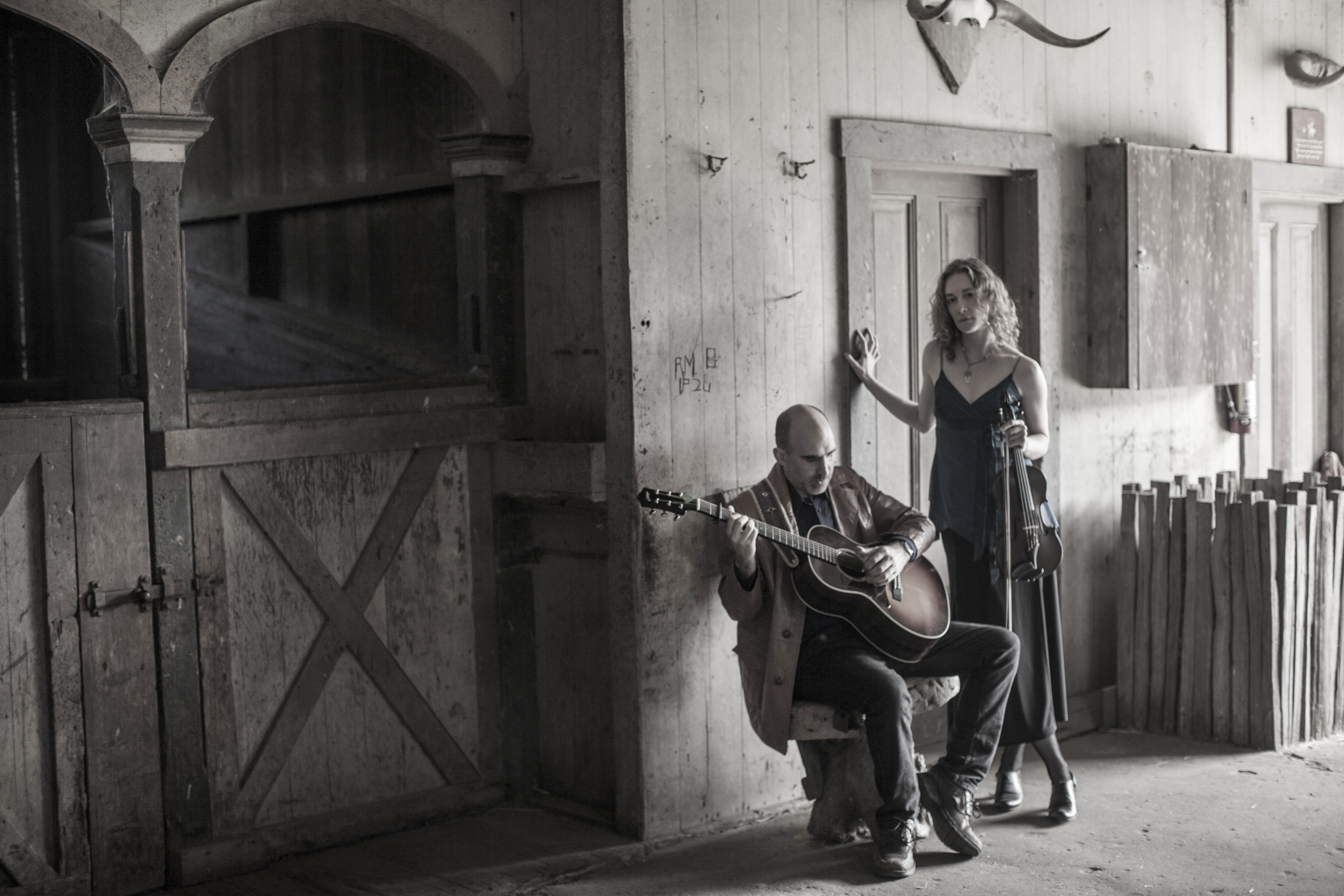 Dan Frechette & Laurel Thomsen posing with their instruments in a barn