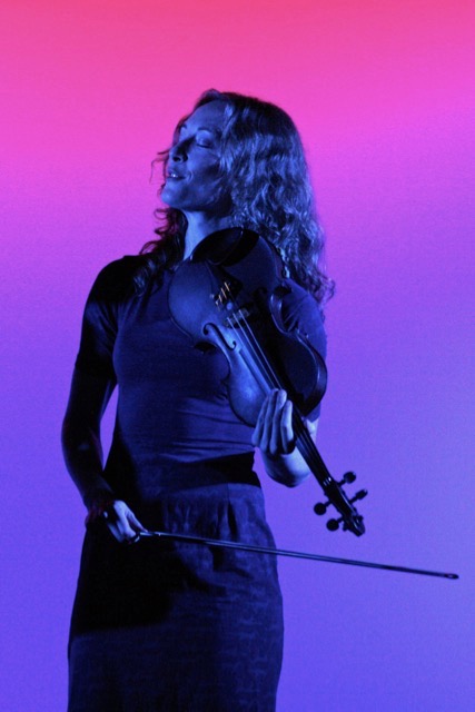 Laurel Thomsen performing on stage with a glowing purple background