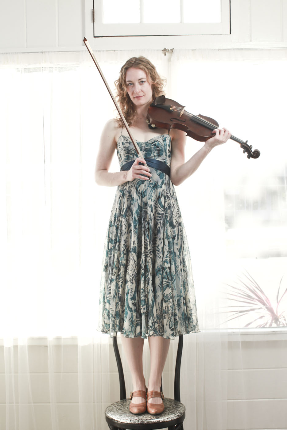 Laurel Thomsen standing on a chair with her violin