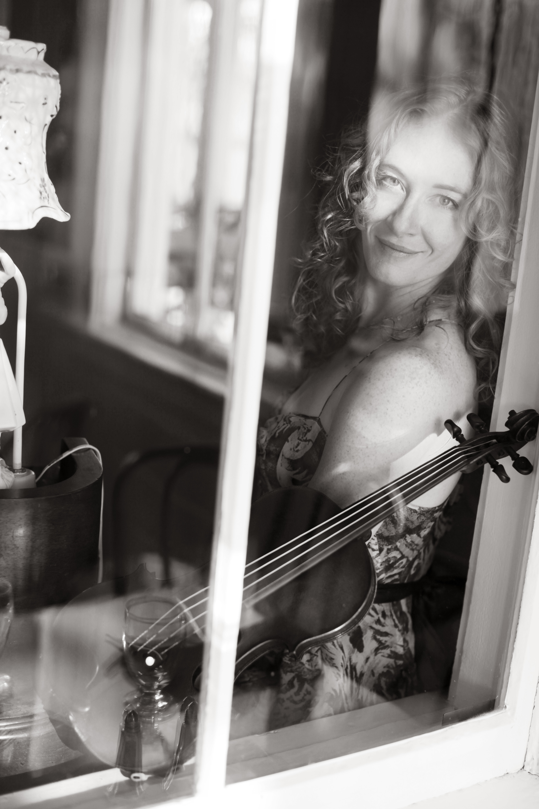 Laurel Thomsen and her violin through a window